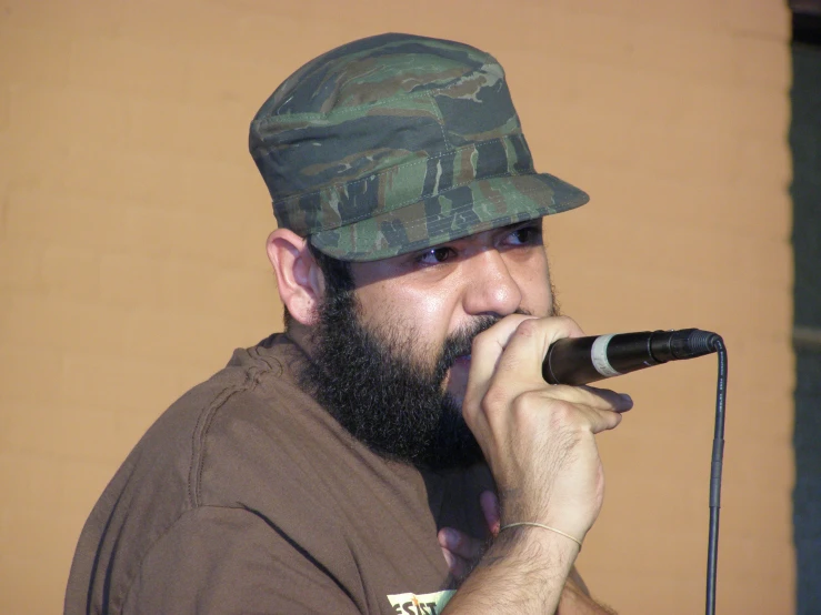 a man in camo hat singing into a microphone