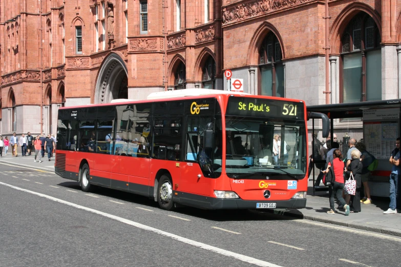 a red and black bus on a street next to buildings