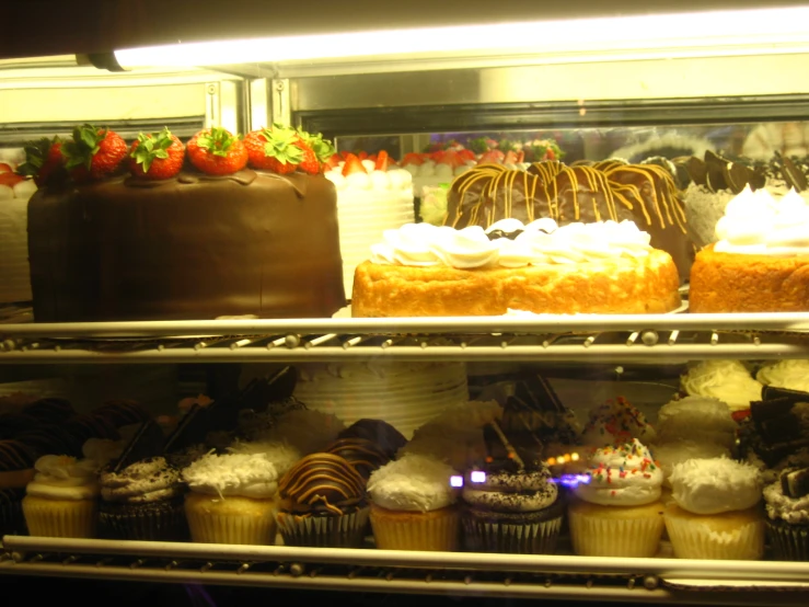 several trays of cakes sitting inside a display case