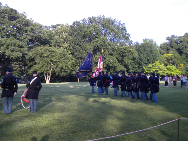 men in uniforms hold flags as they watch others