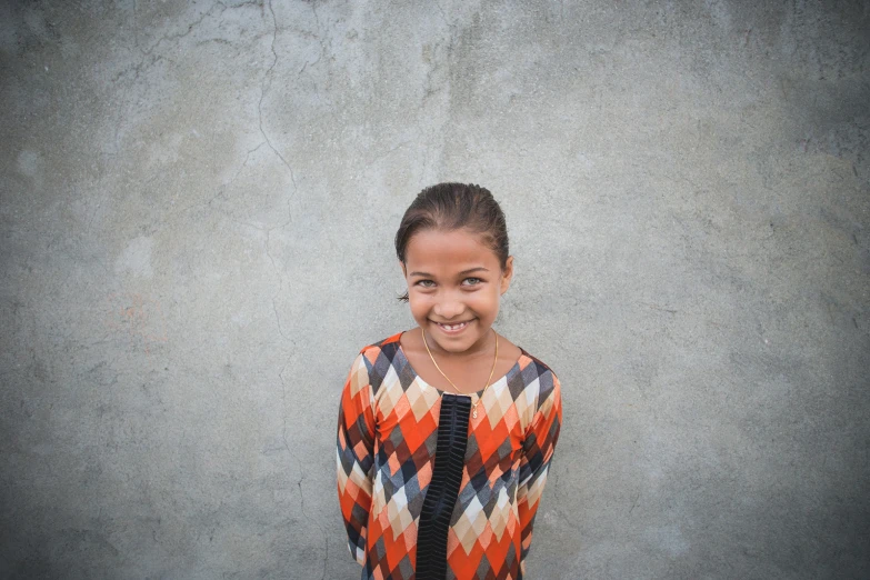 a  smiles brightly in front of a wall