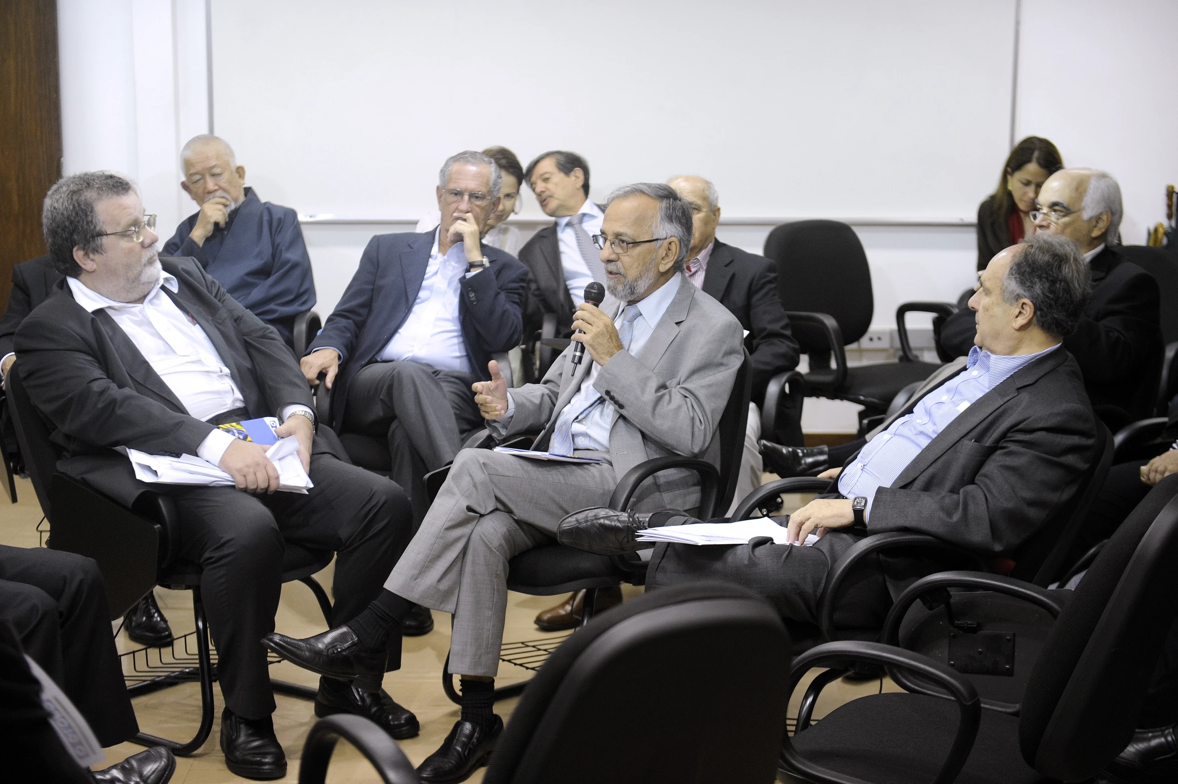 people in suits and ties sit around in chairs