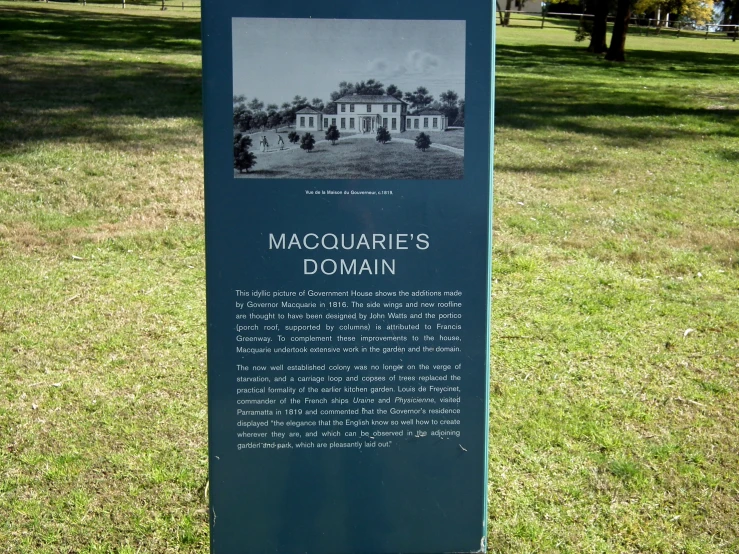 a sign is set in grass in front of a building