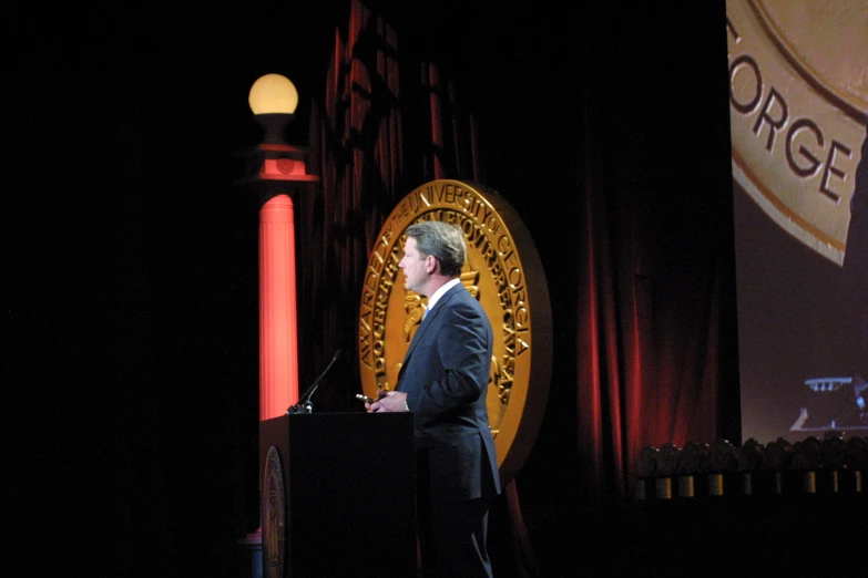 a man speaking at a podium while wearing a suit and tie