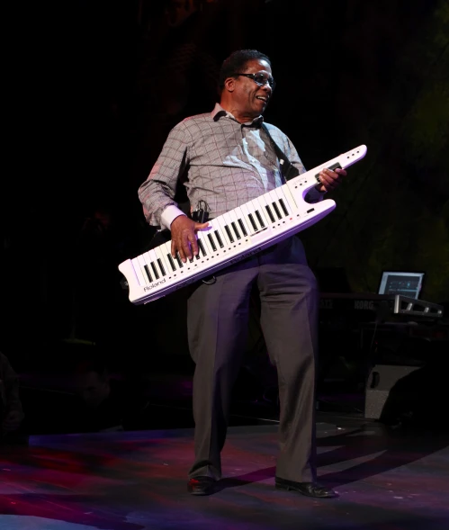man with large white keyboard on stage in dark room