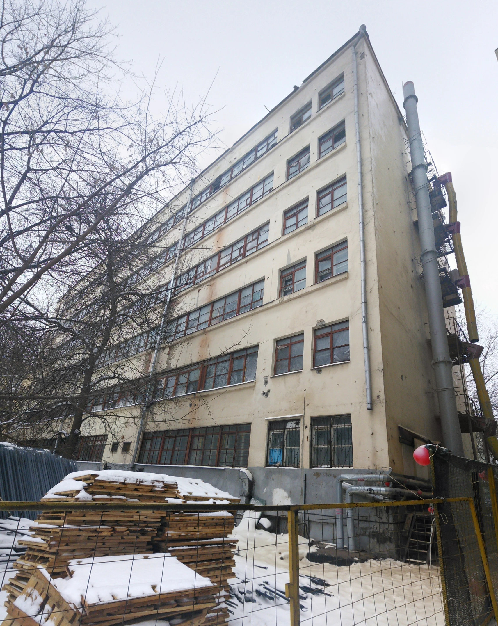 a building surrounded by wooden logs and a snow - covered ground