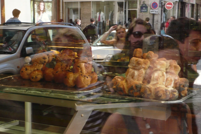 a reflection of a man in a glass window with a tray of food on it