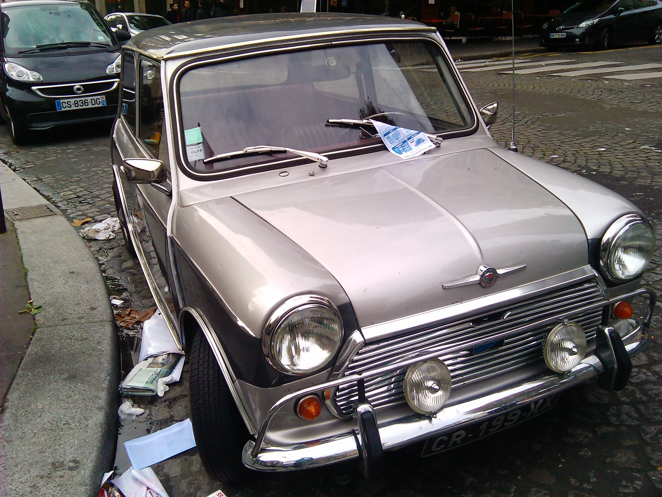 a car parked on the side of the road with a blue piece of paper tied to the front