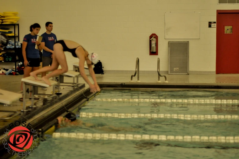 a girl diving into the pool while other people watch