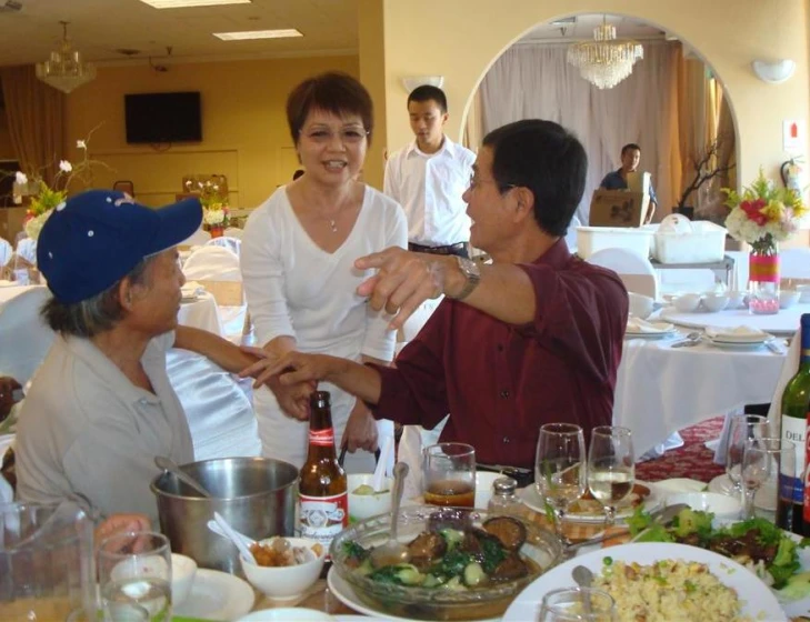 three people shaking hands in front of a table with food