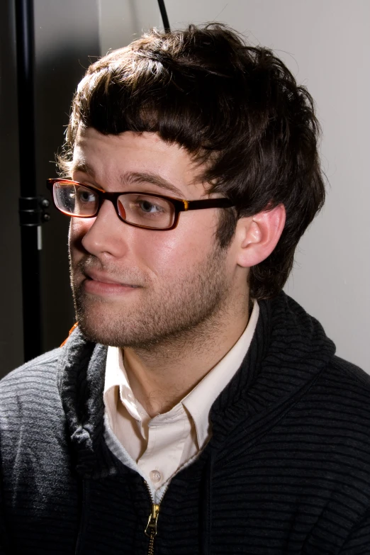 a man wearing glasses and a sweater looking away