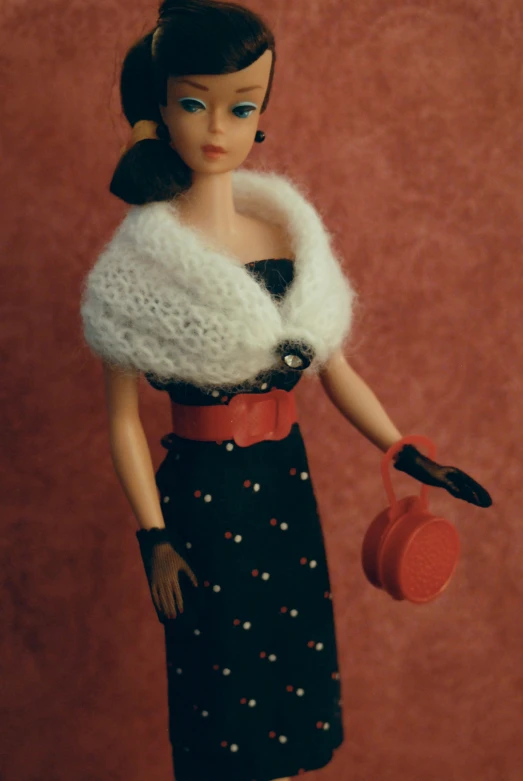 a close up of a doll with a dress and coat