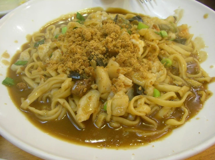 a white bowl full of food with some noodles on top