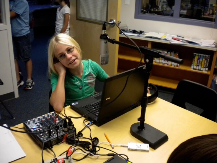 a little girl is working on a laptop in a radio studio