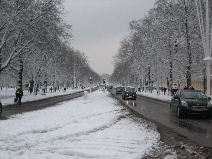 many people walking in the snow near some cars