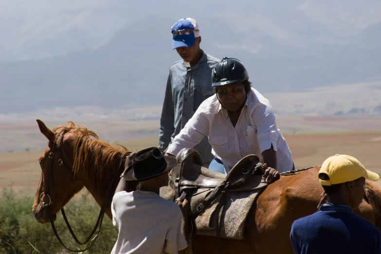 two men on horses looking at a woman sitting in the saddle