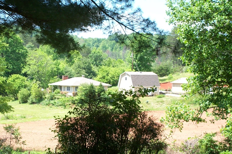 an open field with houses on it and trees around