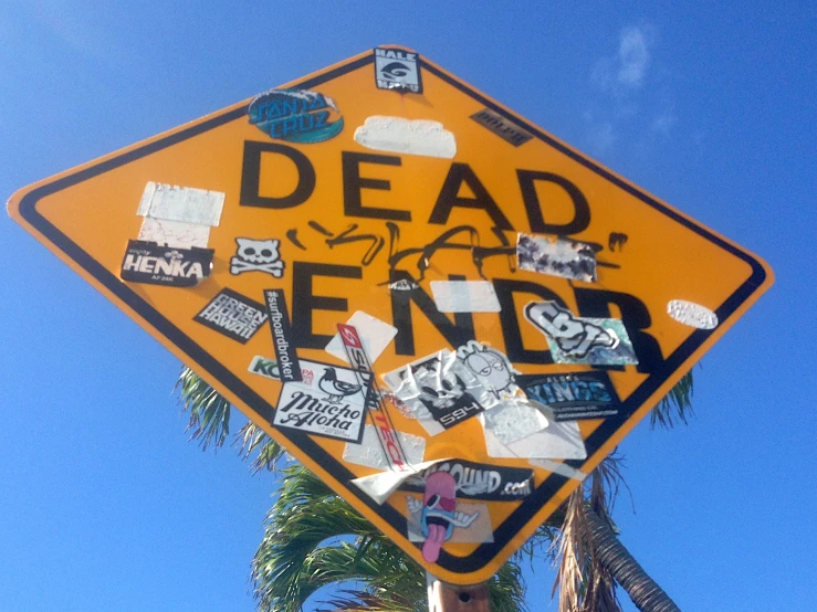 a dead end street sign with various stickers on it