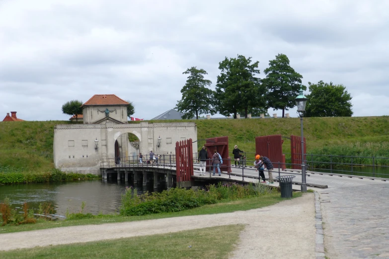 several people walking over a wooden bridge near the water