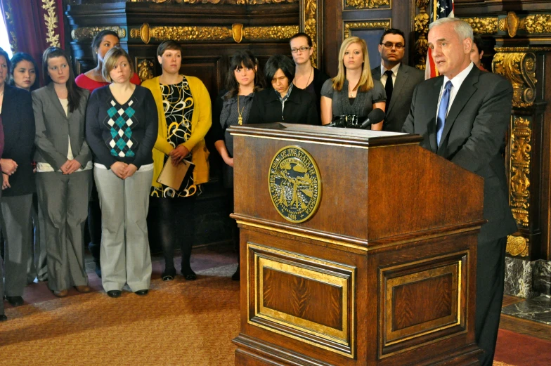 several people stand together behind a large podium