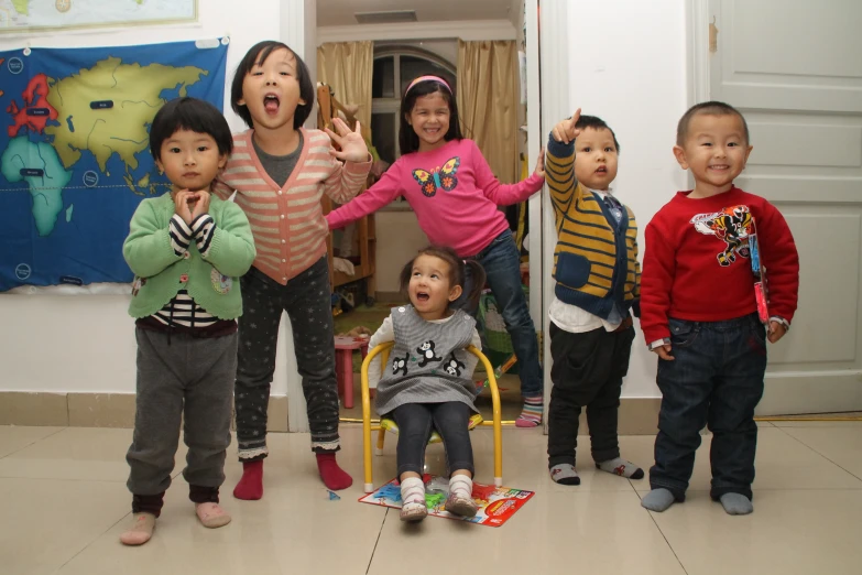 small children standing in front of a door with one boy on a toy horse