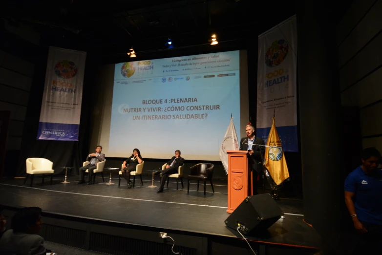 a number of people sit in chairs on a stage