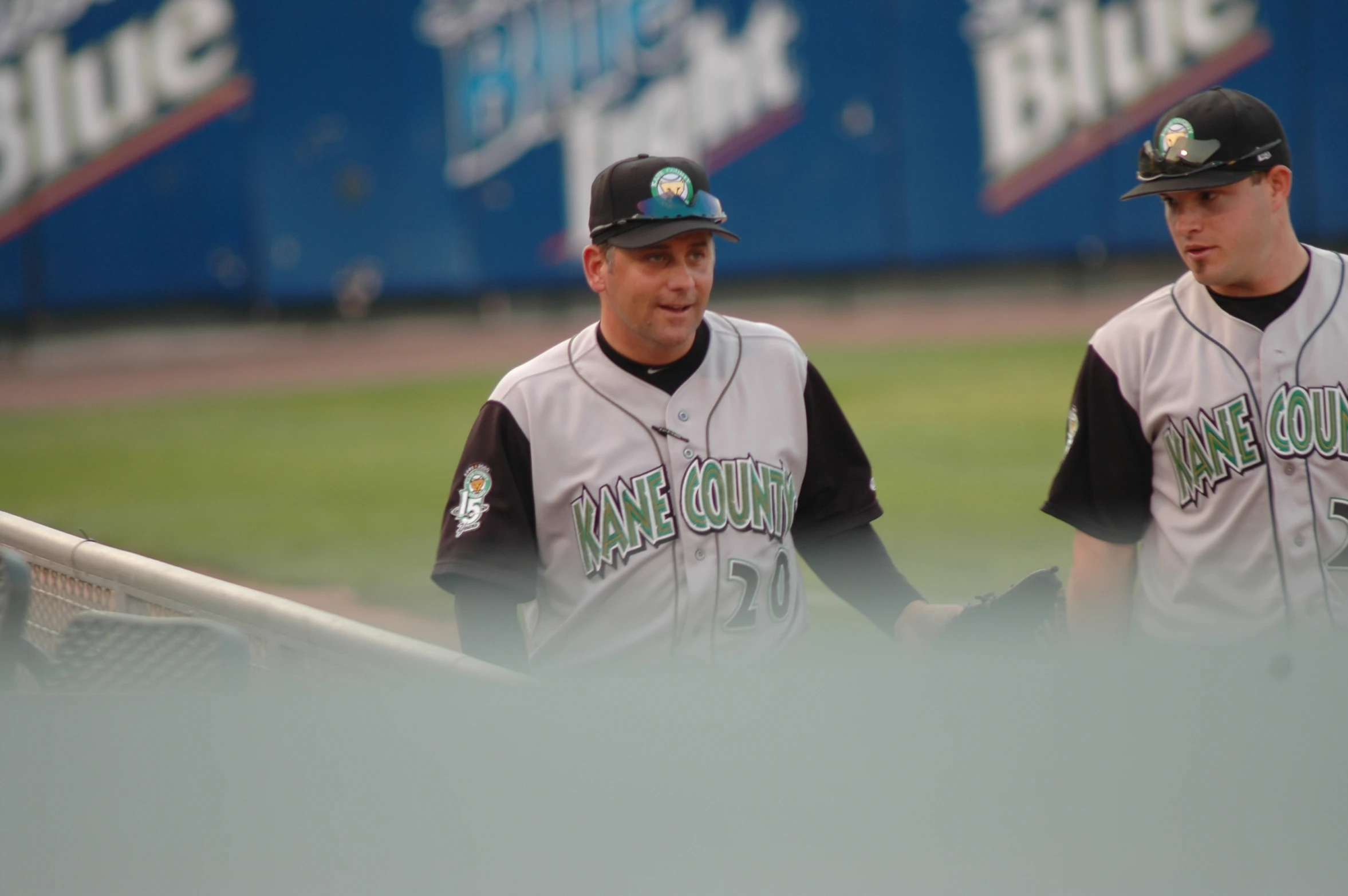 two baseball players stand by the dugout