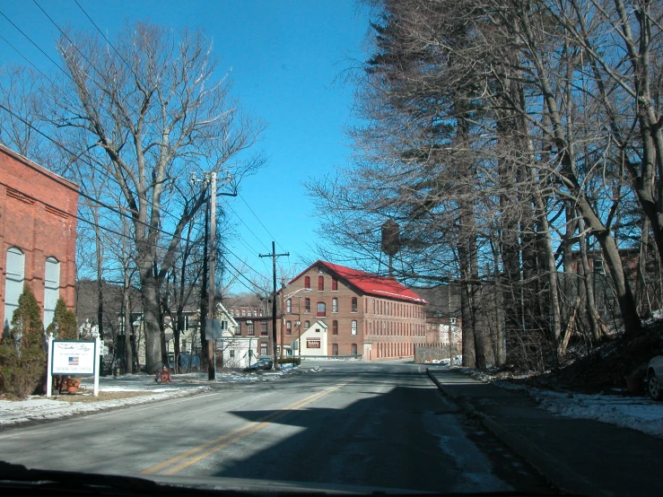 a road near some trees and a building with red roofs