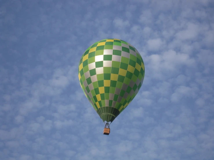 the green and white  air balloon is soaring through the air