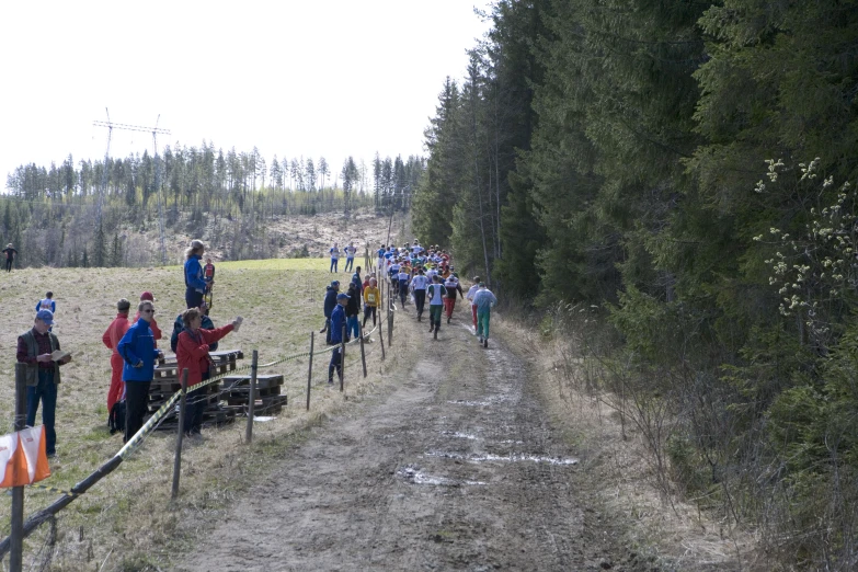 many people are on the path by a fence and trees