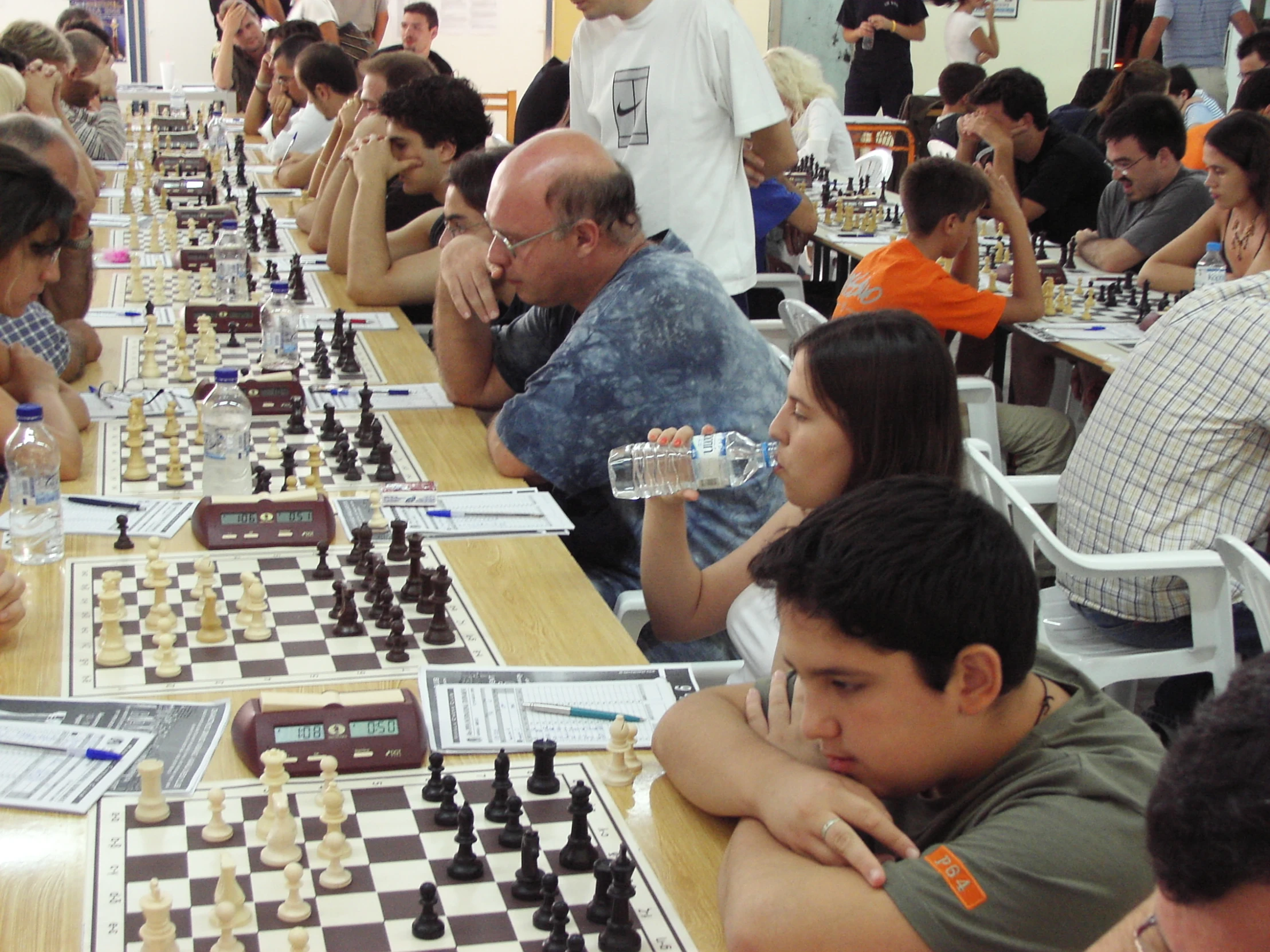 people are sitting at long tables while playing chess