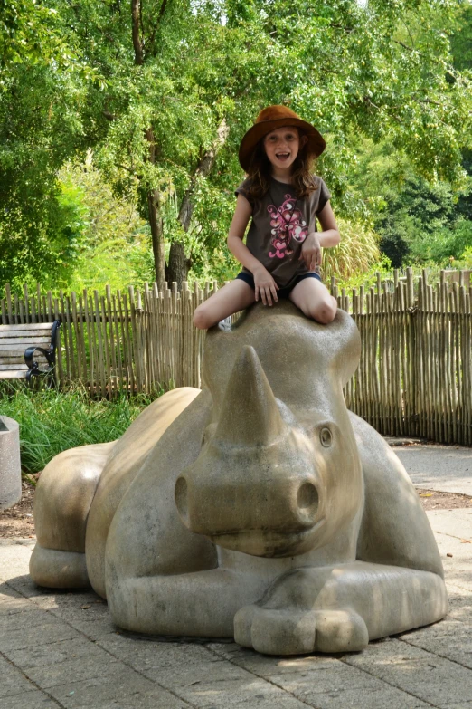 a little girl sitting on the back of an elephant statue