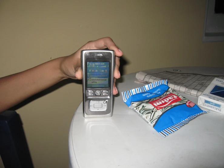 someone holding a flip cell phone near a small table