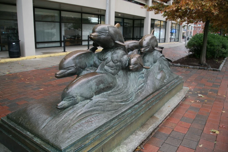 bronze statue of dolphins swimming on a stone slab