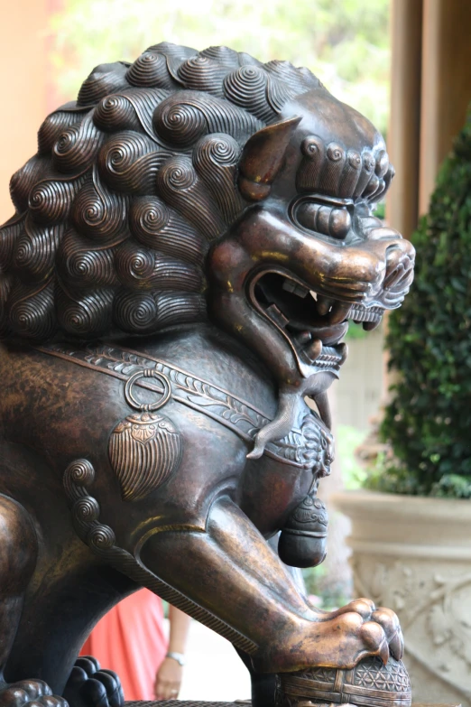 a lion statue sits on the sidewalk next to a vase