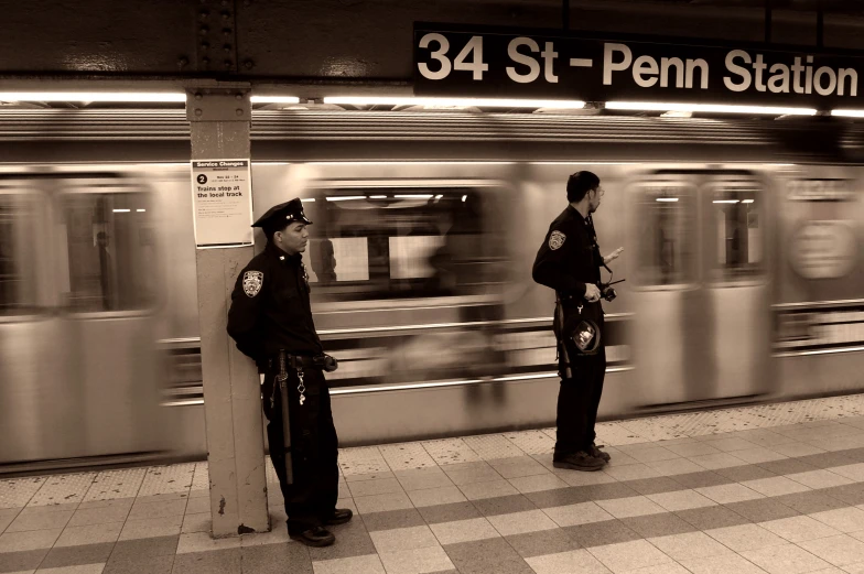 two security officers stand in front of a subway train