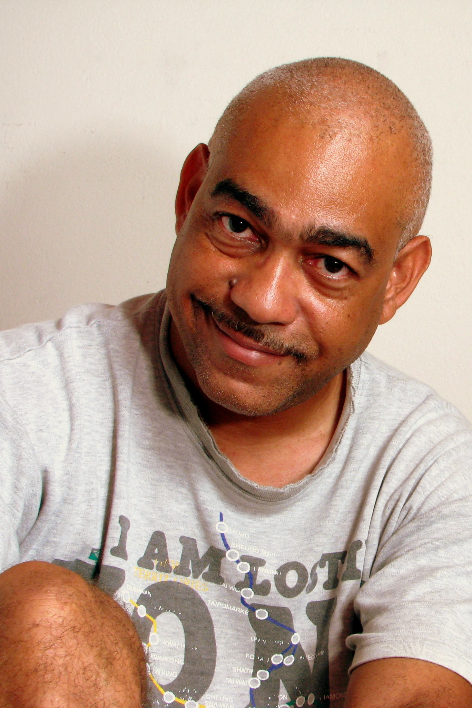 a bald man with gray shirt and white wall