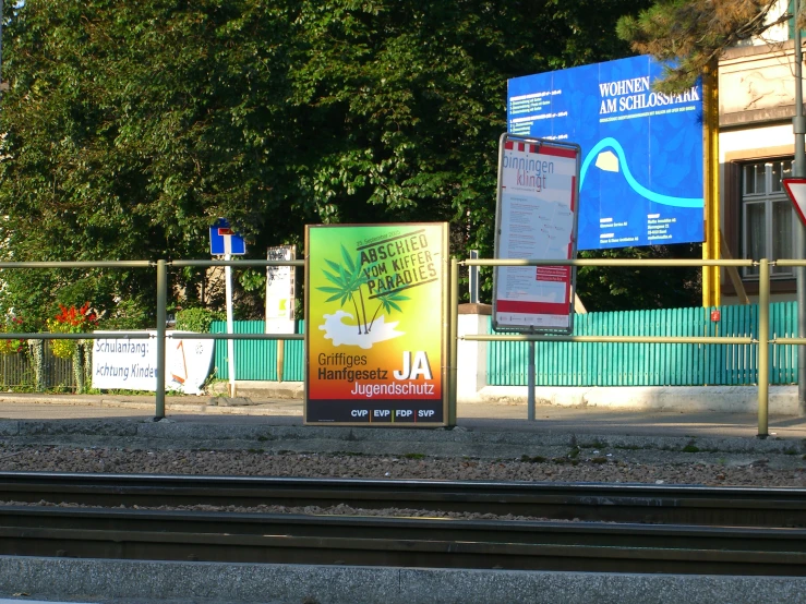 a train track on a sunny day with signs next to the tracks