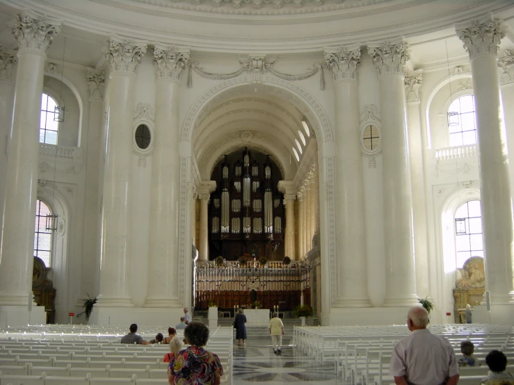 people sit in chairs around the altar during an immaculately decorated church