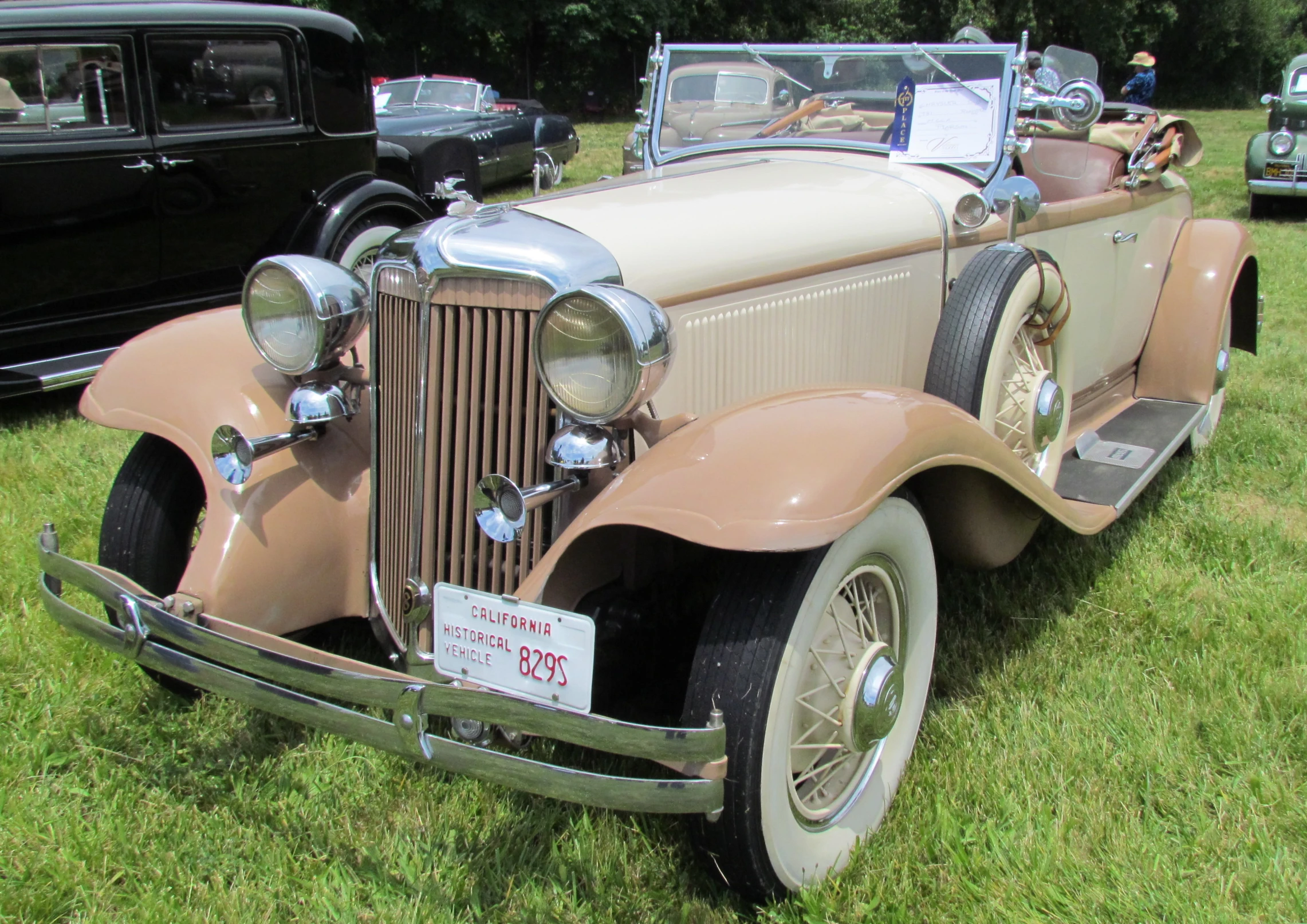 a very old fashion style car parked in a grassy area