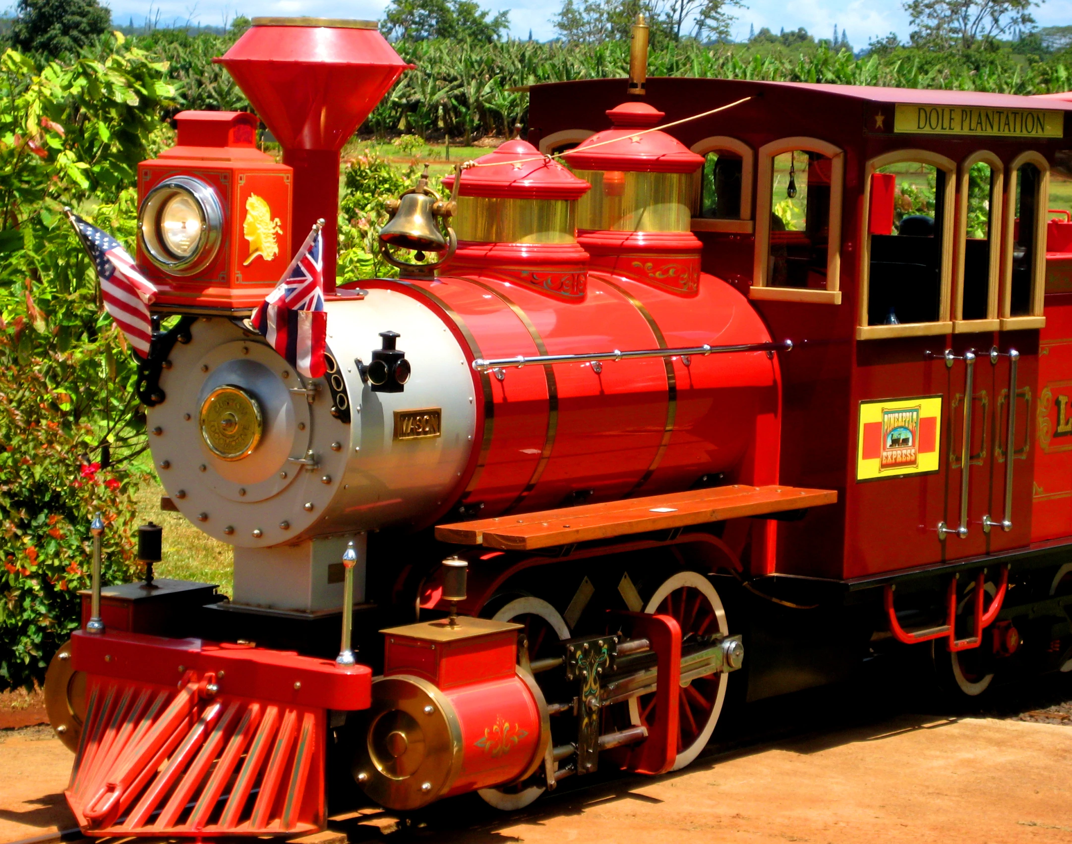 a red train with flags on it sitting in the street