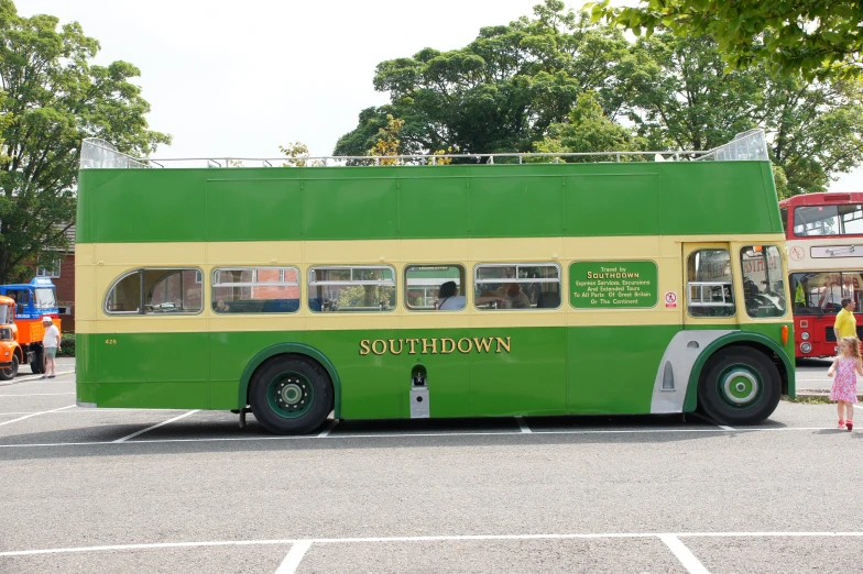 a large bus that is green with people standing outside