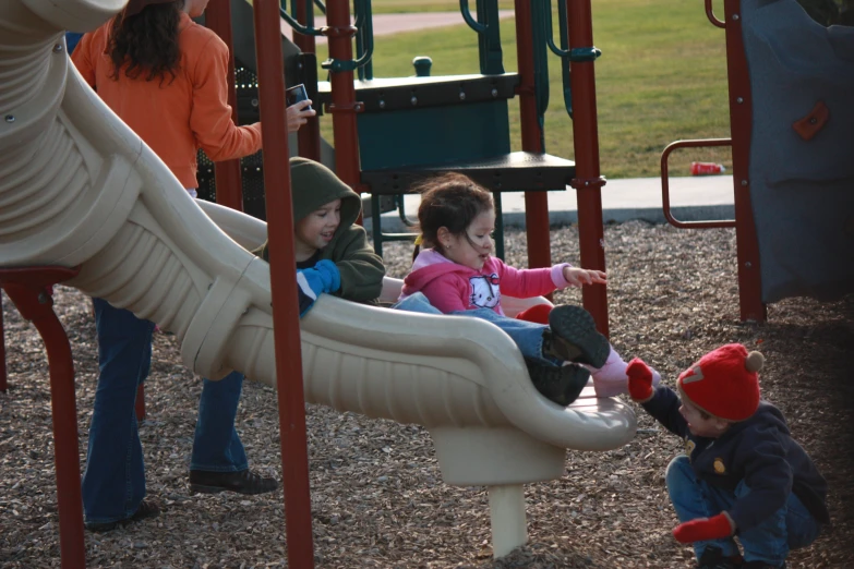 several children play in a park near a slide