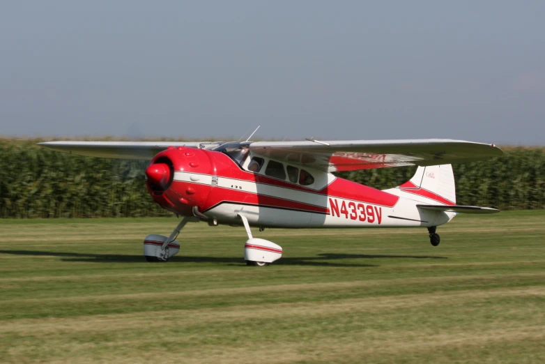 a small red and white plane parked on the grass