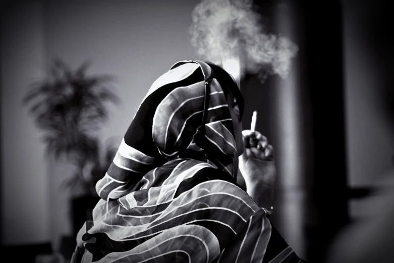 a woman with a striped robe on her head smoking a cigarette