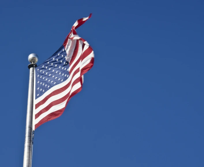 the american flag flying in a bright blue sky