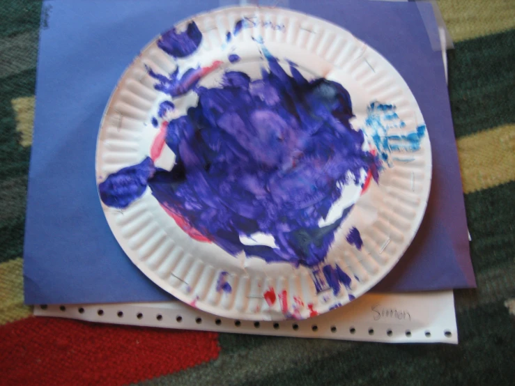 a paper plate covered in purple paper sitting on top of a blue table cloth