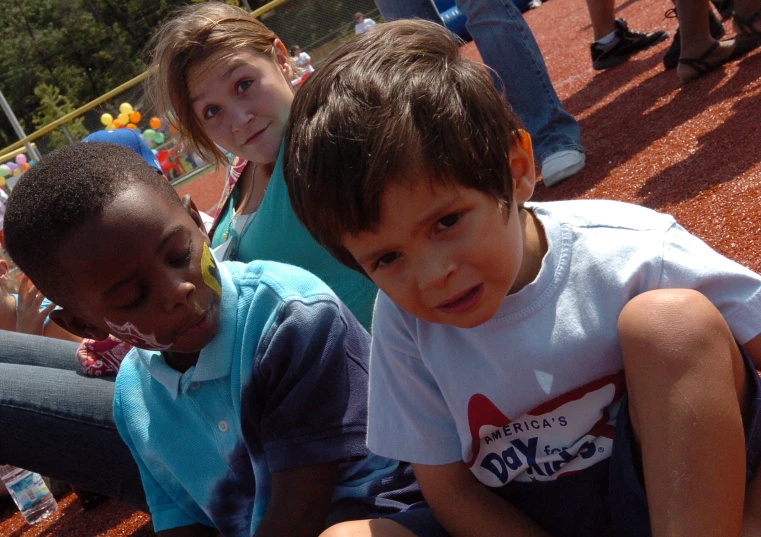 three s sitting on the bleachers at a baseball game