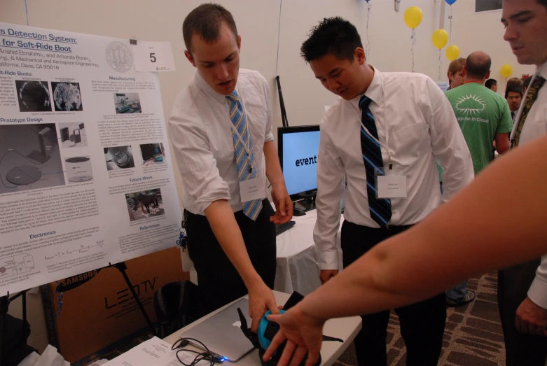 some men standing around looking at a laptop