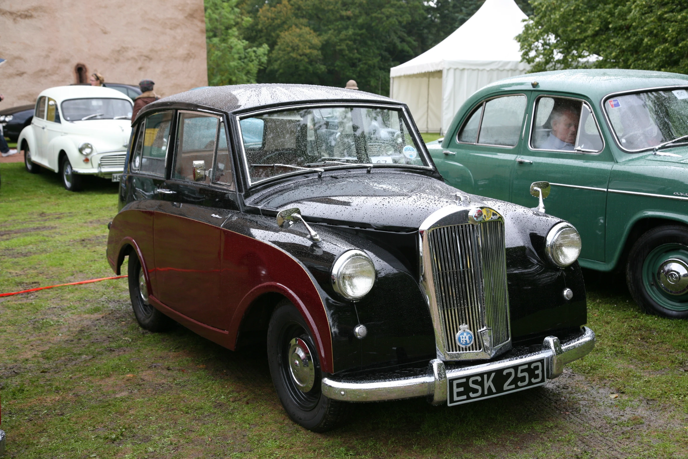 an old car sitting in the grass with another car behind it